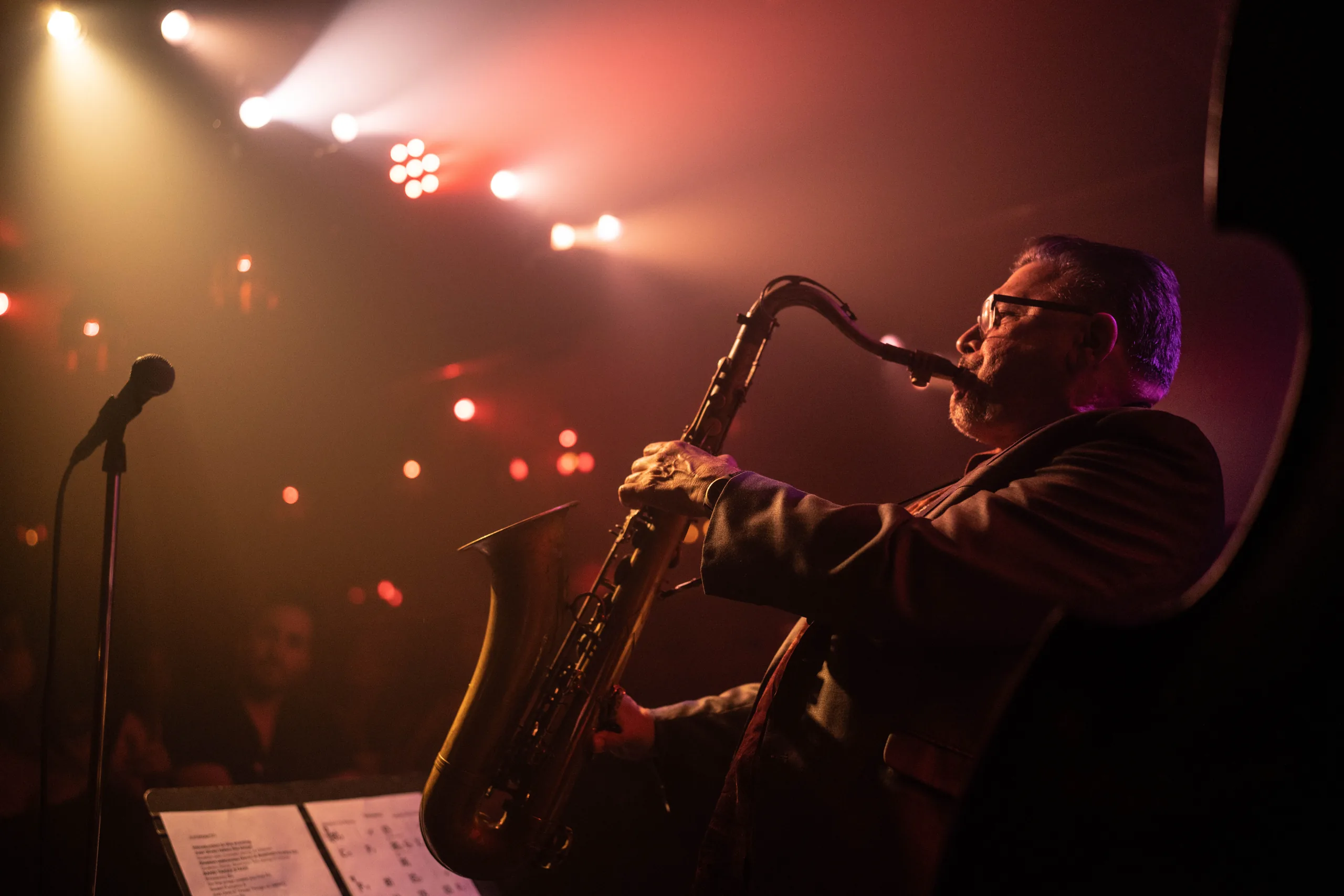 Man playing saxophone in a technicolor-lit club