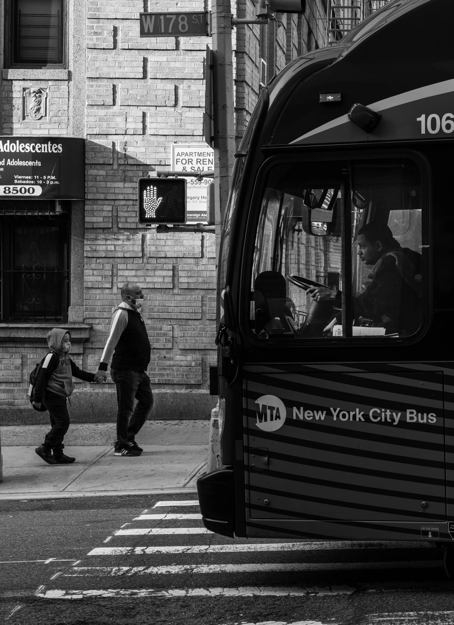 Parent and child strolling in Washington Heights, juxtaposed against a bus