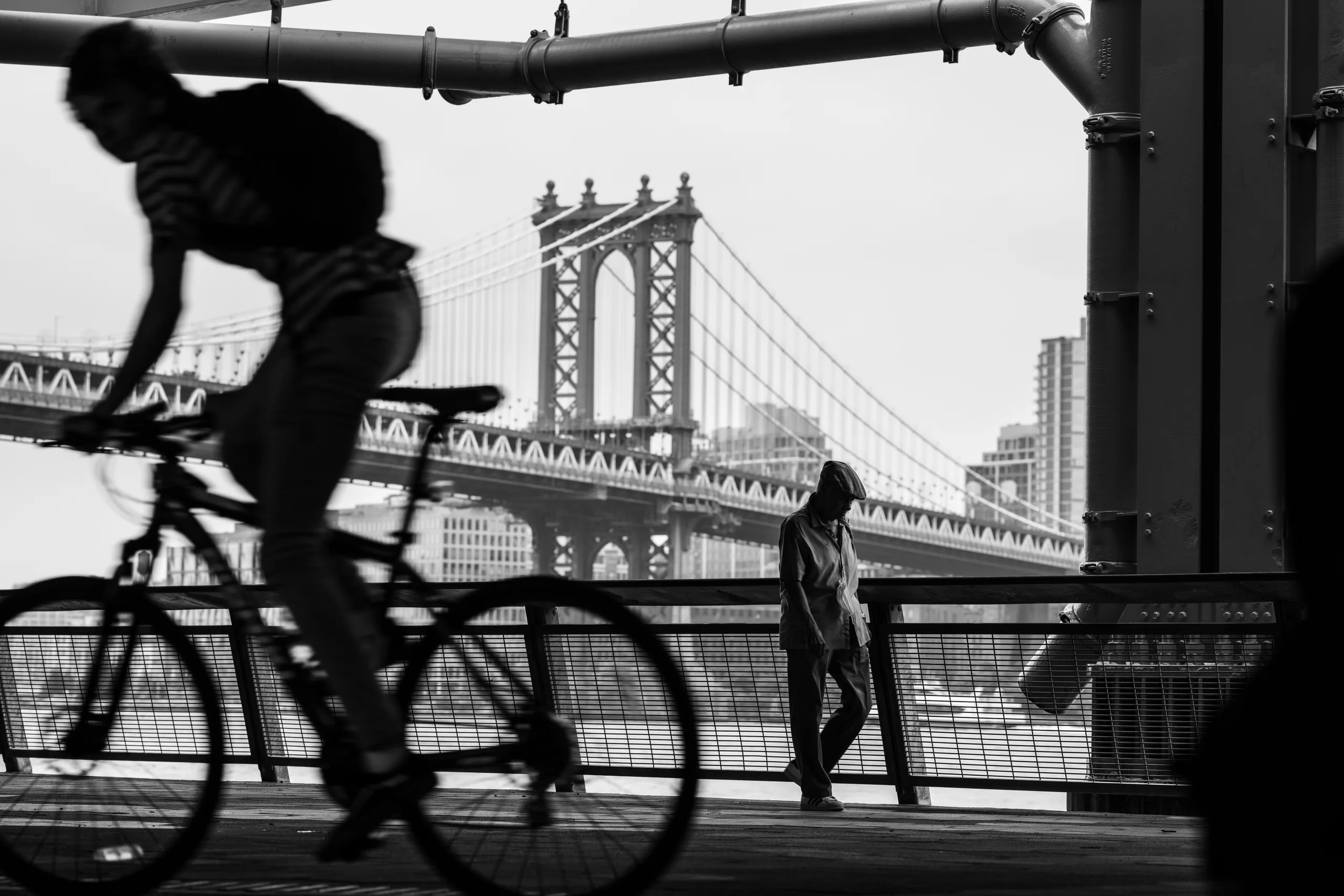 bicyclist and walker next to Manhattan bridge